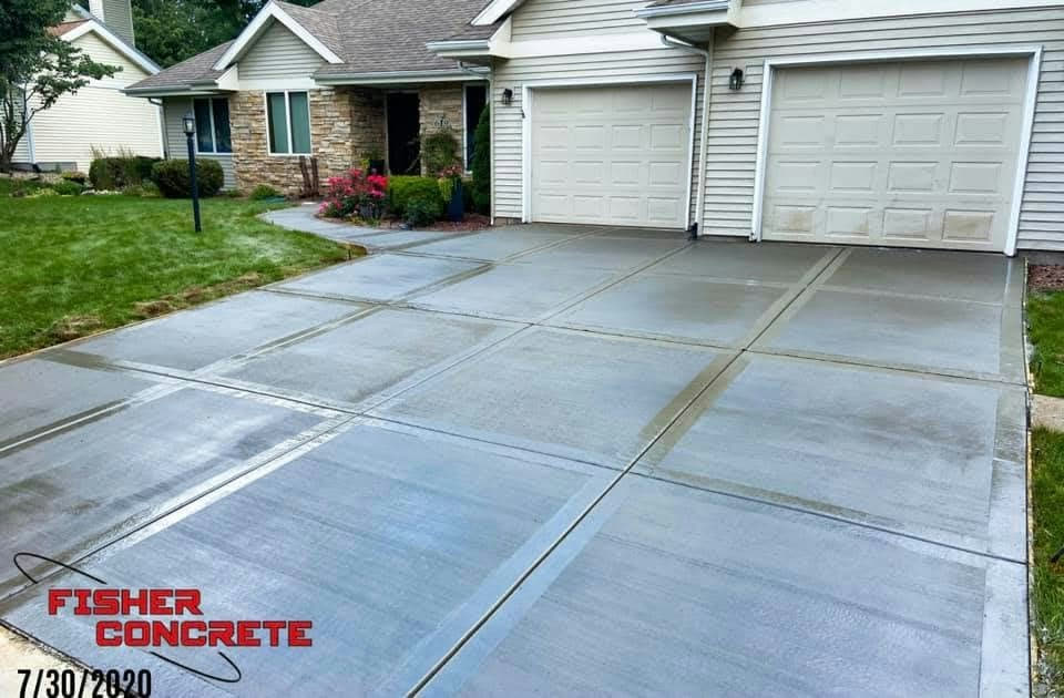 Wide replacement driveway with ribbon banding at a two-car garage