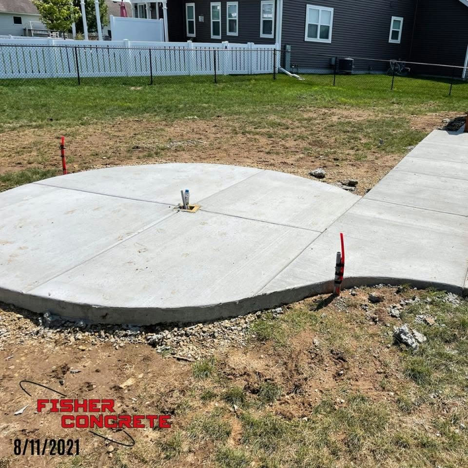 Round concrete pad with connecting sidewalk in a fenced yard