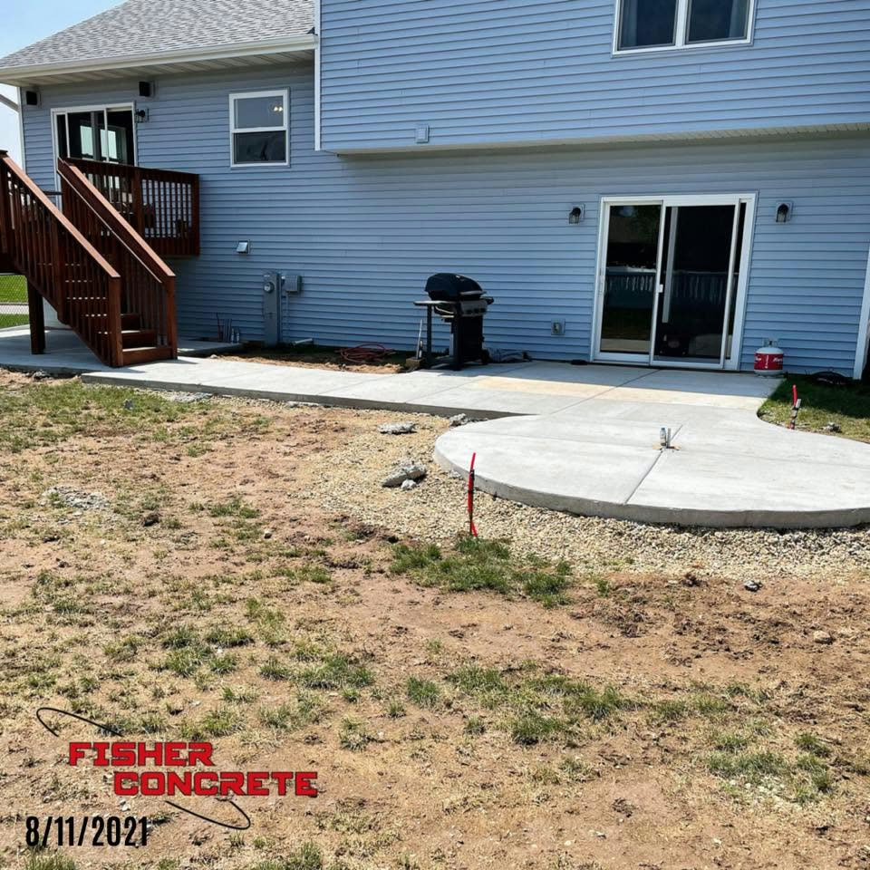 Round concrete patio joined to a walkway in a backyard