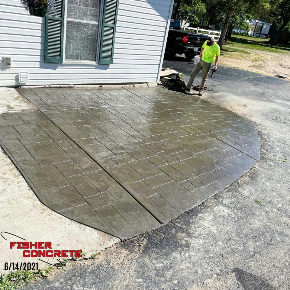 Stamped concrete patio with ashlar slate pattern beside a white house