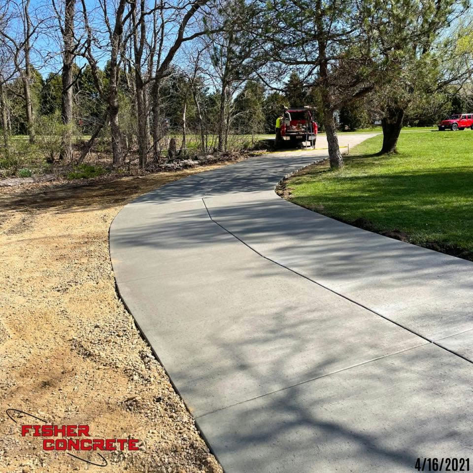 Long curved concrete driveway through a wooded lot