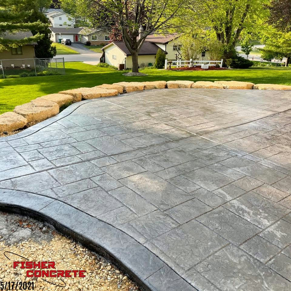 Charcoal stamped concrete patio with boulder retaining wall