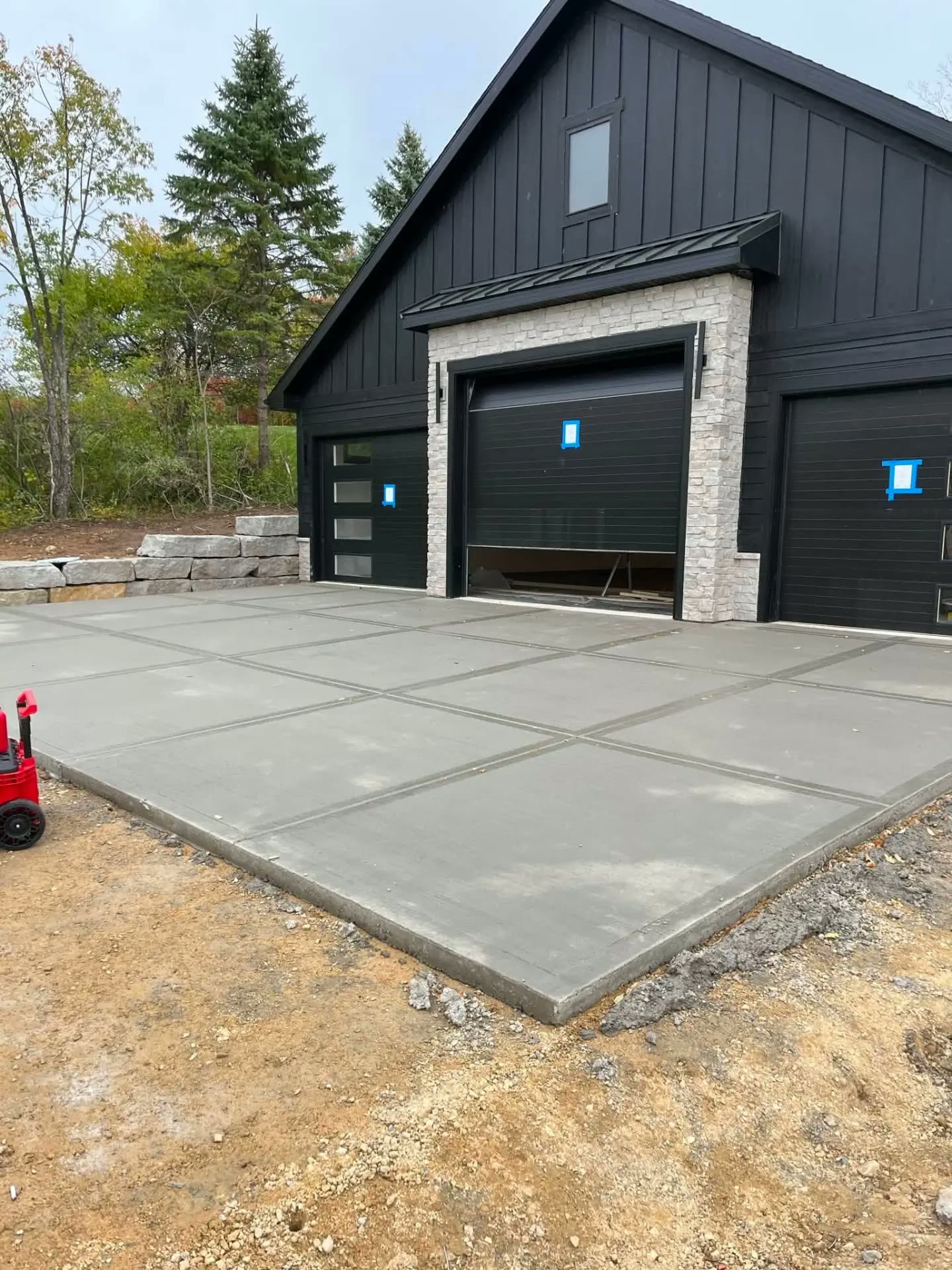 Concrete apron and pad in front of a black pole barn shop