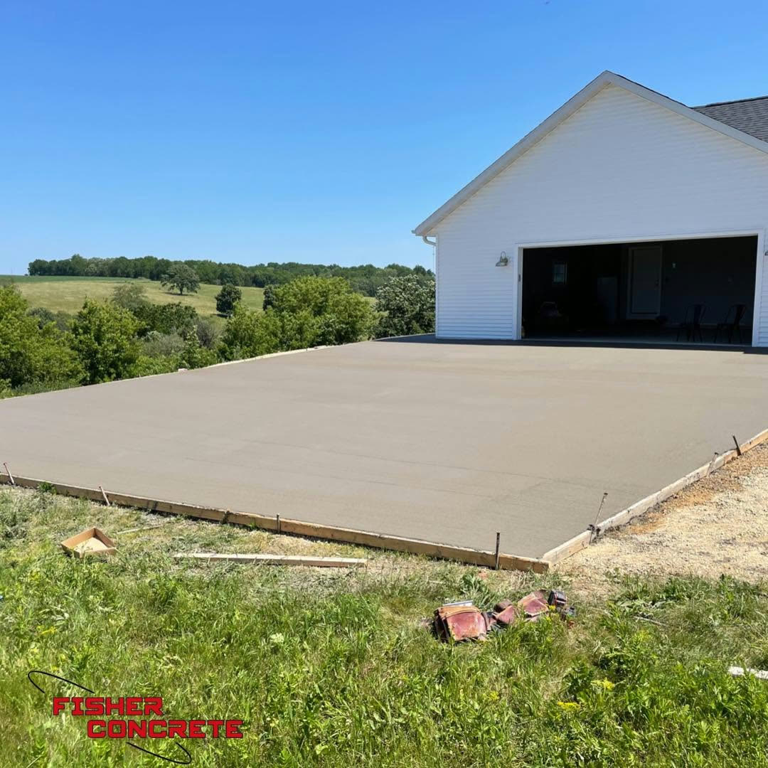 Fresh shed floor slab poured next to a white garage