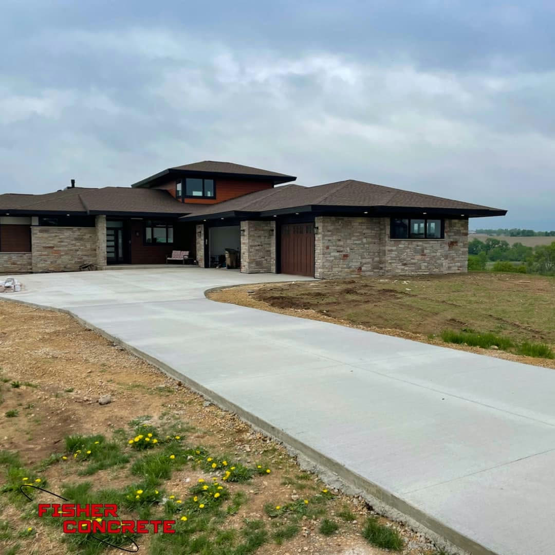 Long residential driveway leading to a stone-front home